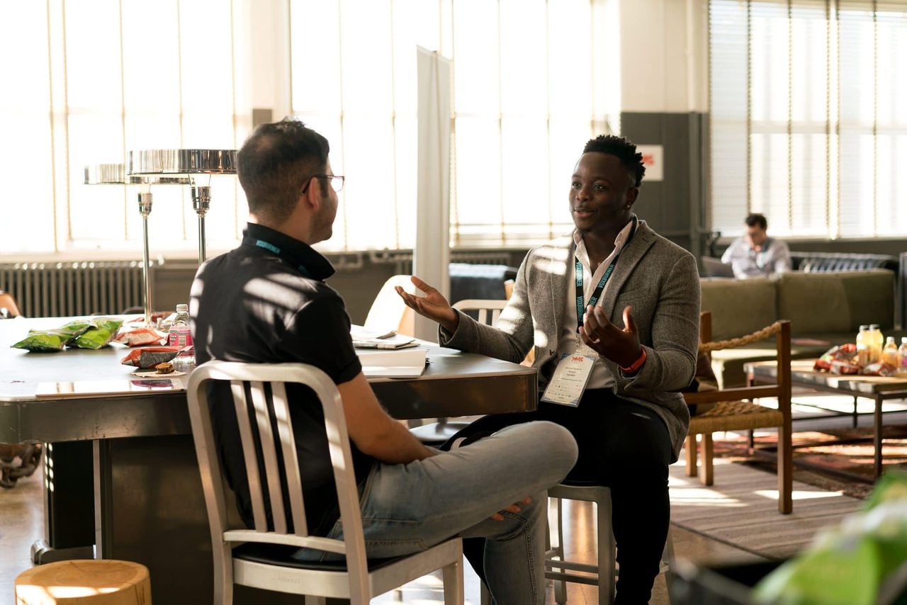 Home Two men having a casual discussion in a bright indoor setting, highlighting mentorship.